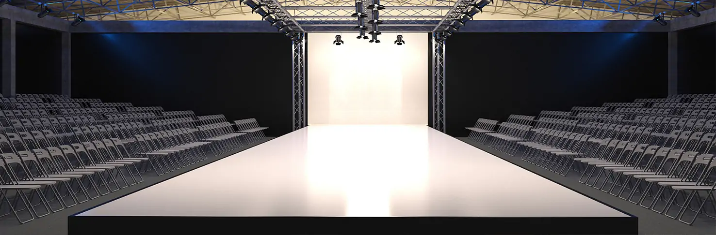 A sleek, professionally set up catwalk stage by Neves Media in Panama City, Florida, with secure stage decking and modern lighting. Rows of empty chairs flank the runway, ready for an audience, demonstrating the customizable and safe staging solutions available for diverse events.